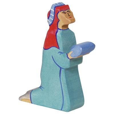 Wooden figurine of a person wearing a blue outfit and red head covering on a white background