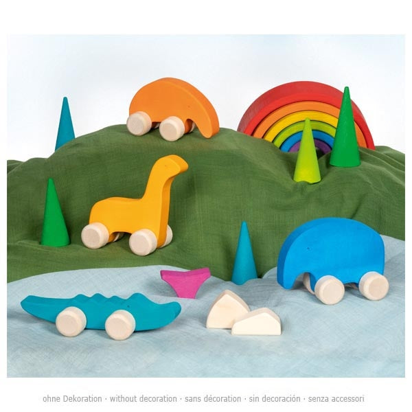 Colorful wooden toy cars and a dinosaur on a green and blue fabric background with rainbow and trees.
