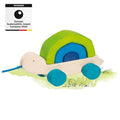 Wooden toy turtle with green shell and blue wheels on a white background, featuring the German Sustainability Award 2024 badge.