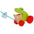Toy frog with red wheels and a wooden boat on a white background