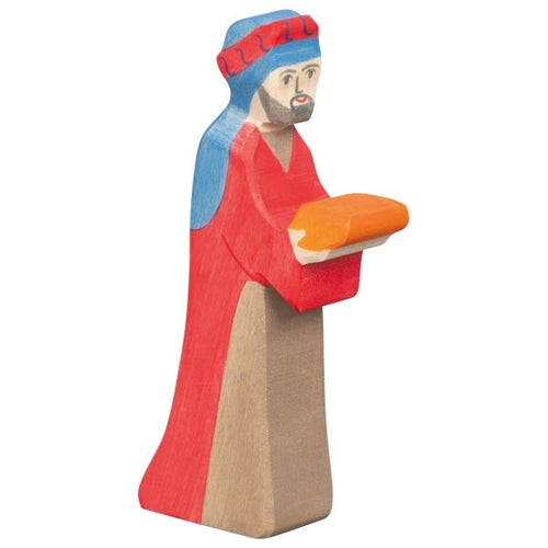 Wooden figurine of a character in red robe and blue headgear holding an orange object on a white background