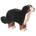 Wooden dog figurine with black, brown, and white colors on a white background