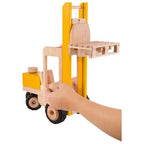 Wooden toy forklift with a hand holding it on a white background